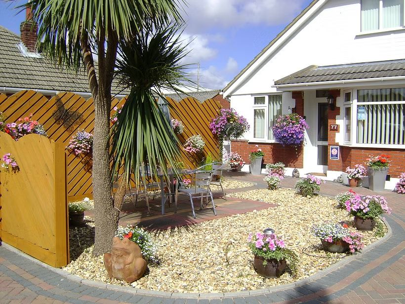 Coast 77 B&B - Charming Exterior with Palm Tree and Colorful Garden